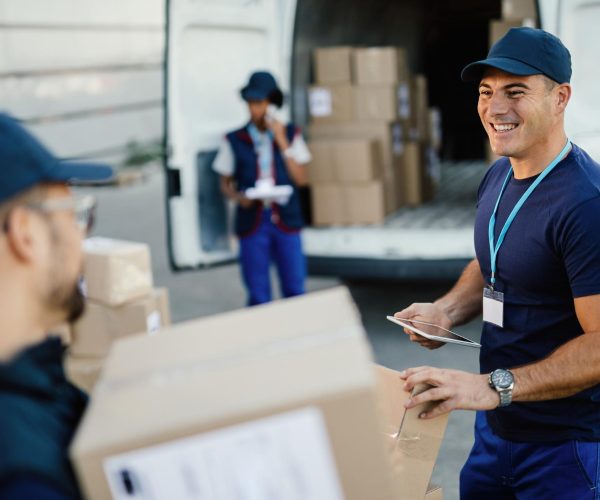 happy-manual-worker-using-touchpad-while-communicating-with-his-coworker-organizing-package-delivery